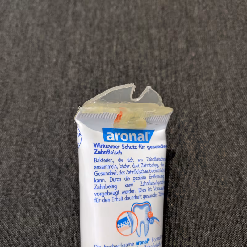 The first proof of concept: a blob of clear hot glue moulded onto the crimped top seam of a toothpaste tube