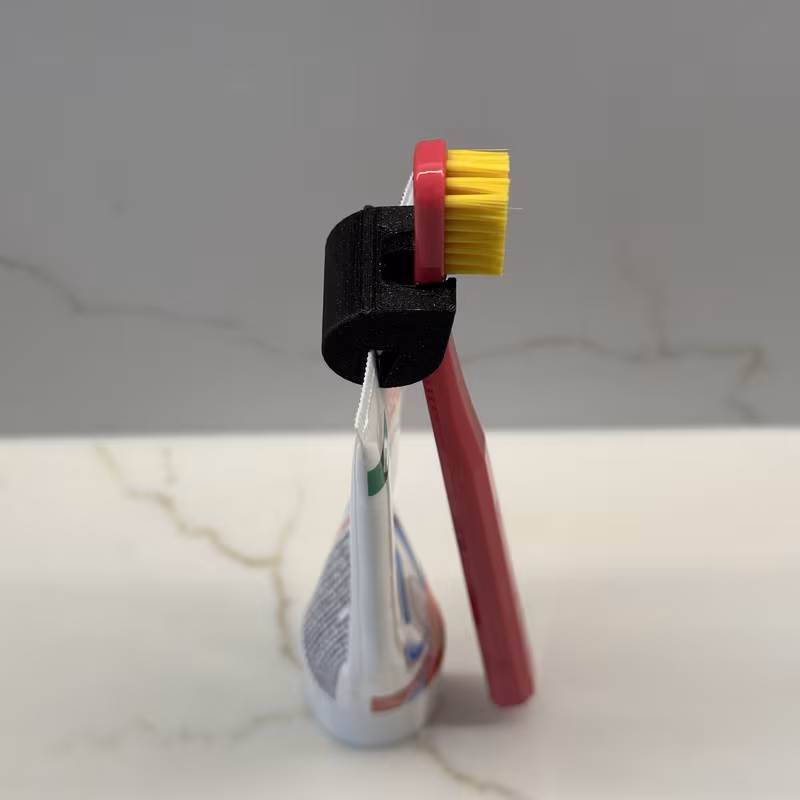 Side view of the final holder, showing the brush handle resting against the tube and the head hanging clear