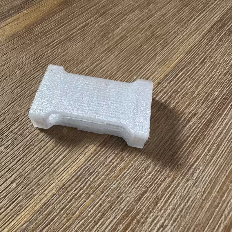 The same part printed in white filament, showing the layer lines across its top face