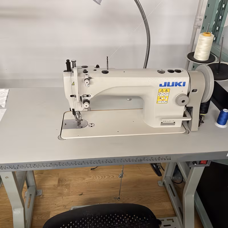 An industrial Juki walking-foot sewing machine set up on its table with spools of thread beside it